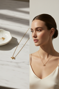 Delicate minimal gold necklace with geometric pendant on white marble surface